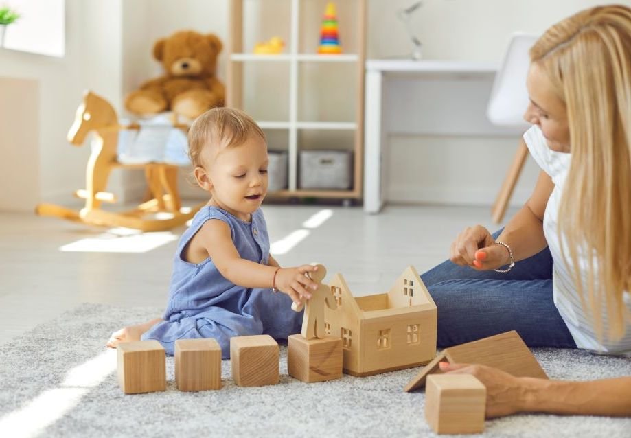 Mother and daughter playing with wooden blocks, house, a person