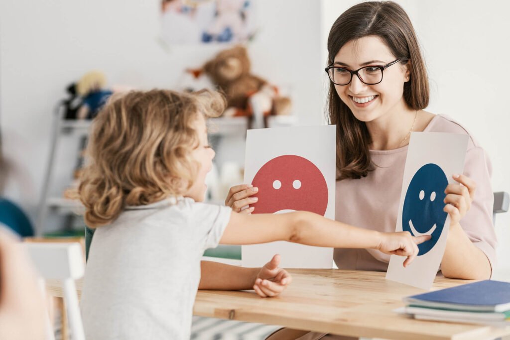 Girl pointing to a happy face emoticon being held a psychologist